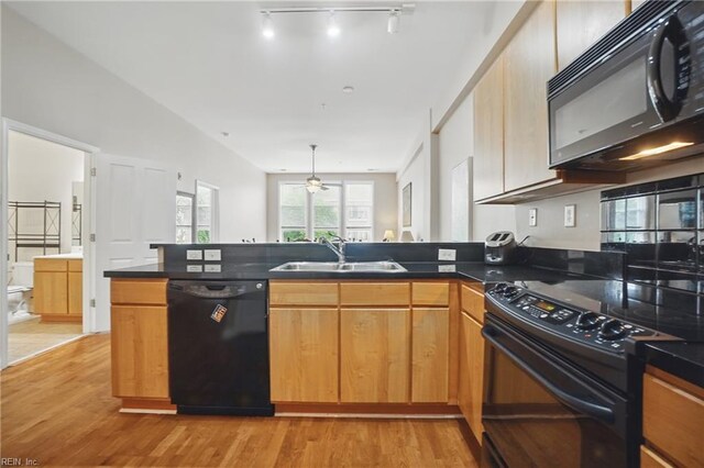 388 Boush St Unit 122, Norfolk, VA 23510 - kitchen featuring black appliances, a sink, a peninsula, light wood-style floors, and dark countertops