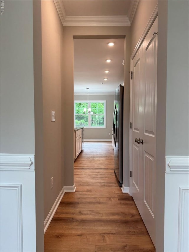 hallway featuring crown molding, light wood-style flooring, baseboards, and recessed lighting