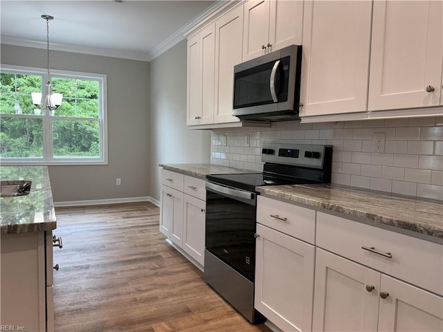 kitchen featuring stainless steel appliances, ornamental molding, baseboards, tasteful backsplash, and light wood-type flooring