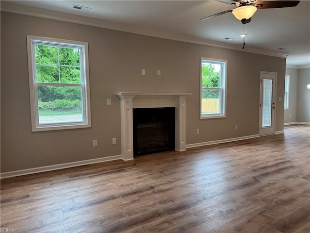 unfurnished living room featuring ornamental molding, a ceiling fan, baseboards, wood finished floors, and a fireplace