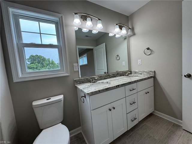 full bathroom with toilet, baseboards, and double vanity