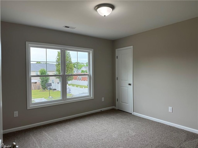 spare room featuring carpet, healthy amount of natural light, and baseboards
