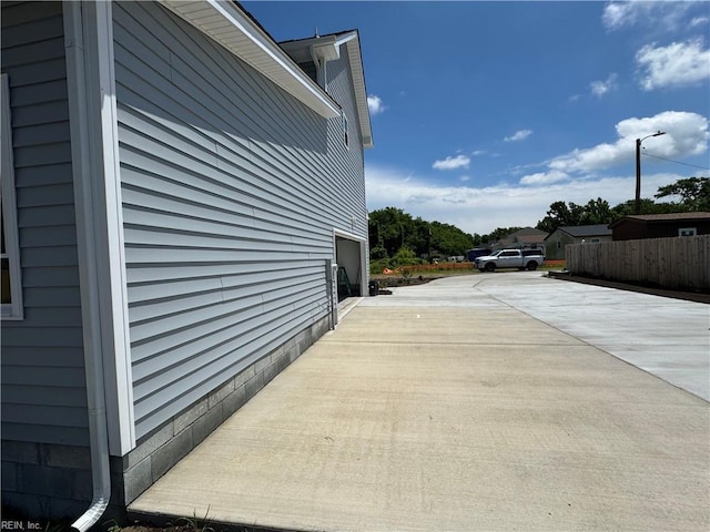 view of side of property with fence and concrete driveway