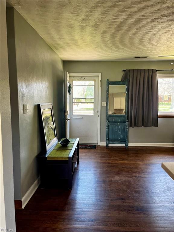 doorway with wood finished floors, baseboards, and a textured ceiling