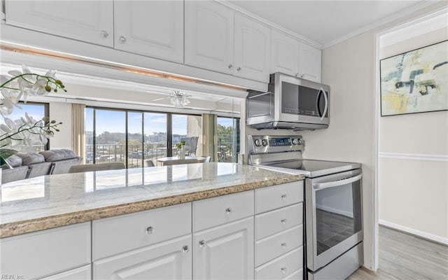 kitchen with stainless steel appliances, crown molding, light wood-type flooring, white cabinetry, and light stone counters