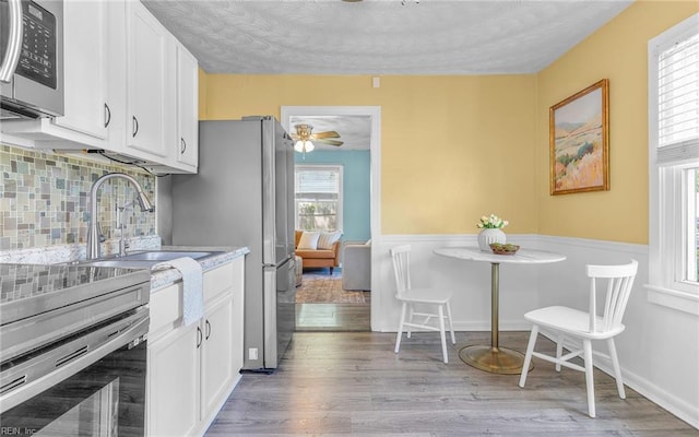 2409 Livesay Rd, Chesapeake, VA 23323 - kitchen featuring appliances with stainless steel finishes, a sink, white cabinets, light wood-style floors, and a textured ceiling
