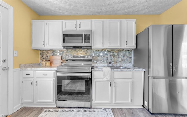 2409 Livesay Rd, Chesapeake, VA 23323 - kitchen featuring stainless steel appliances, a sink, white cabinetry, and light wood-style flooring