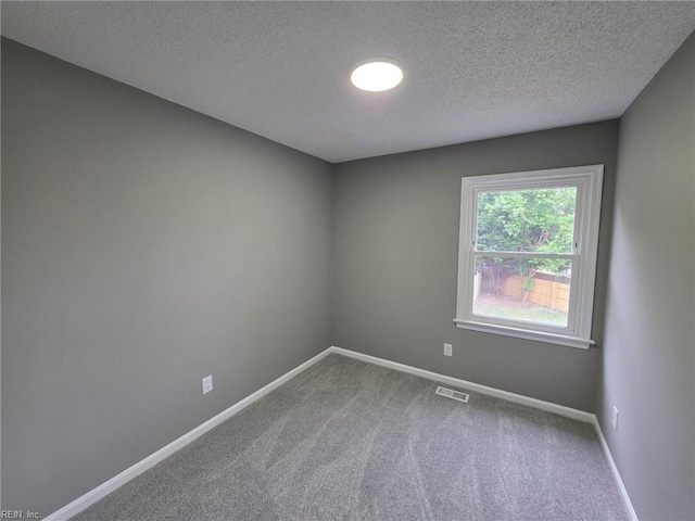 carpeted empty room with a textured ceiling and baseboards