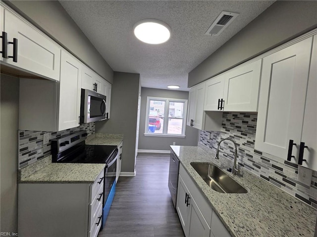 kitchen featuring stainless steel appliances, a sink, a textured ceiling, backsplash, and white cabinets