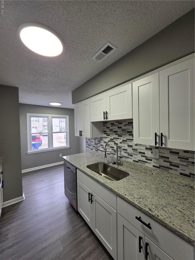 kitchen with a sink, dishwasher, white cabinetry, dark wood-type flooring, and a textured ceiling