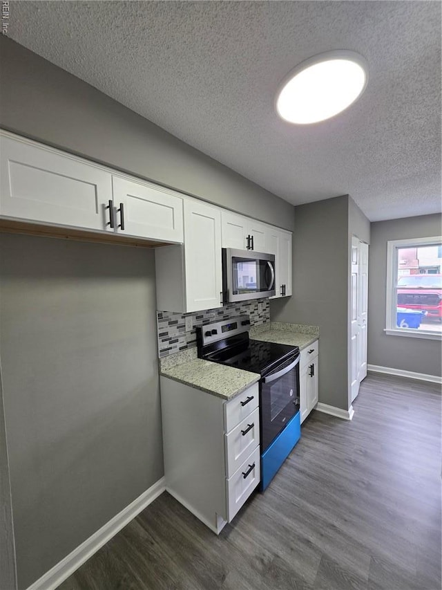 kitchen with stainless steel appliances, dark wood finished floors, a textured ceiling, white cabinetry, and baseboards