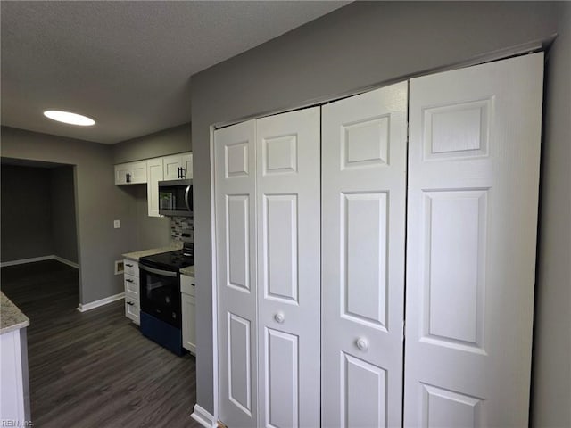 kitchen featuring electric range, stainless steel microwave, white cabinetry, baseboards, and dark wood-style floors