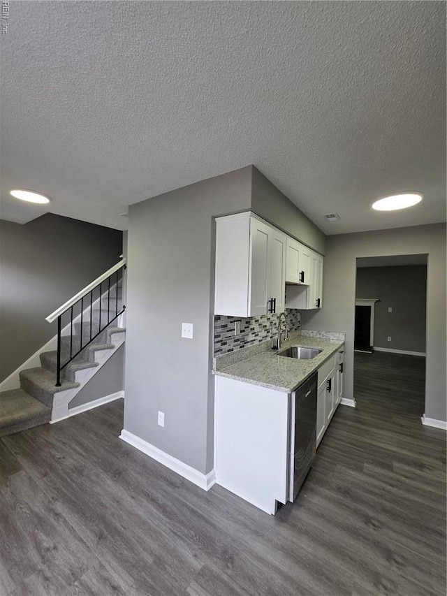 kitchen with a sink, baseboards, dishwasher, white cabinetry, and a textured ceiling