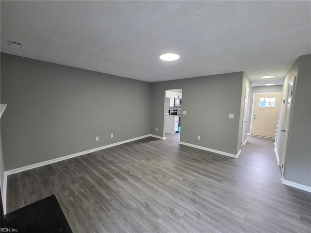 unfurnished living room featuring dark wood-style floors, a textured ceiling, and baseboards