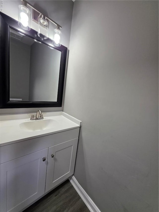 bathroom with wood finished floors, baseboards, and vanity