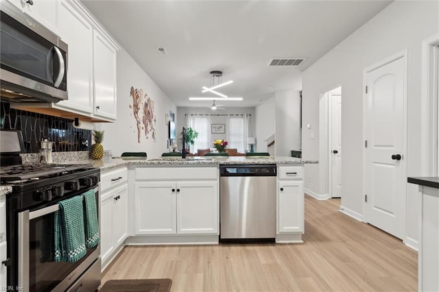 1502 Independence Blvd, Newport News, VA 23608 - kitchen featuring stainless steel appliances, light wood-type flooring, a peninsula, white cabinetry, and backsplash