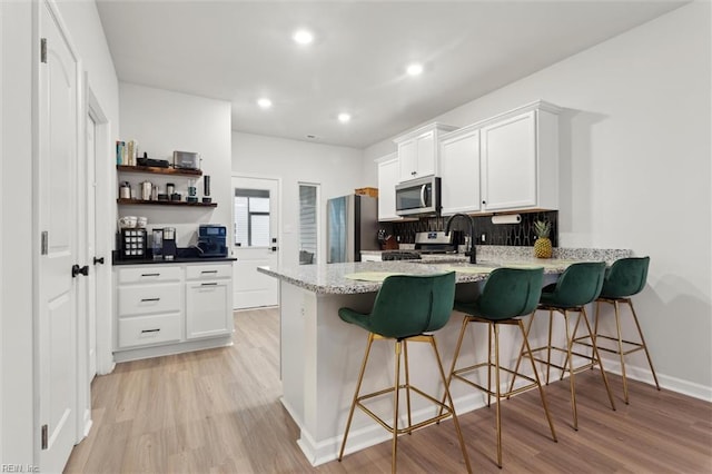 1502 Independence Blvd, Newport News, VA 23608 - kitchen with appliances with stainless steel finishes, a peninsula, tasteful backsplash, light wood-style floors, and recessed lighting