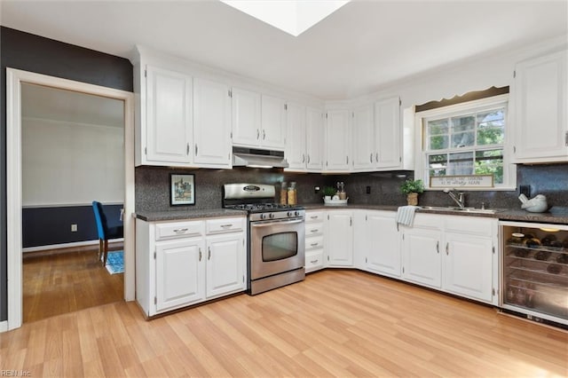611 Windemere Rd, Newport News, VA 23602 - kitchen featuring stainless steel gas range oven, under cabinet range hood, wine cooler, light wood-type flooring, and dark countertops