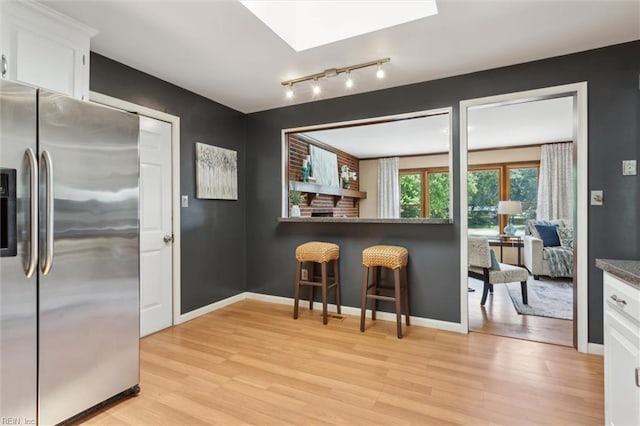 611 Windemere Rd, Newport News, VA 23602 - kitchen with stainless steel fridge with ice dispenser, light wood-type flooring, white cabinetry, a breakfast bar area, and a skylight