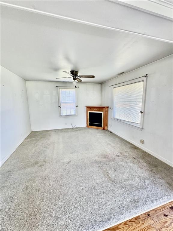 512 S End Rd, Knotts Island, NC 27950 - unfurnished living room featuring a fireplace, carpet, ceiling fan, and baseboards