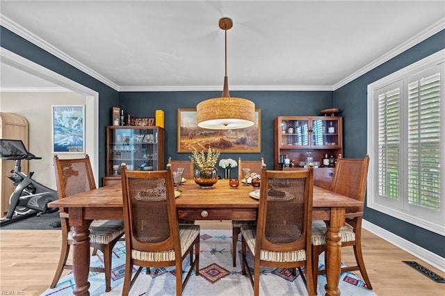 dining area featuring wood finished floors, baseboards, and crown molding