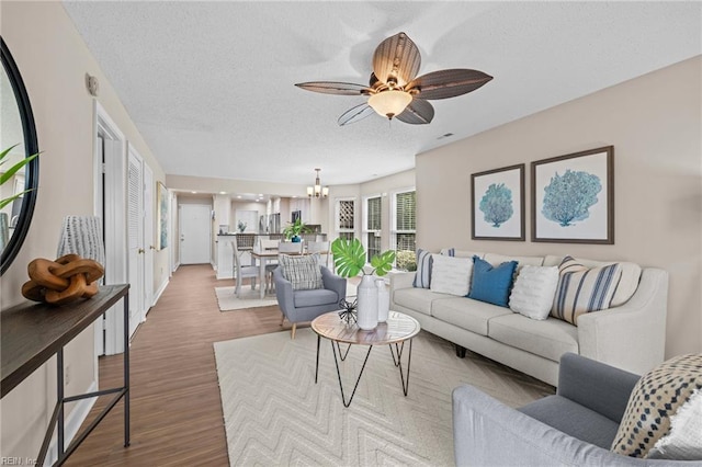living room with wood finished floors, a chandelier, a textured ceiling, and ceiling fan
