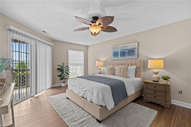 bedroom with baseboards, access to exterior, wood finished floors, a ceiling fan, and a textured ceiling