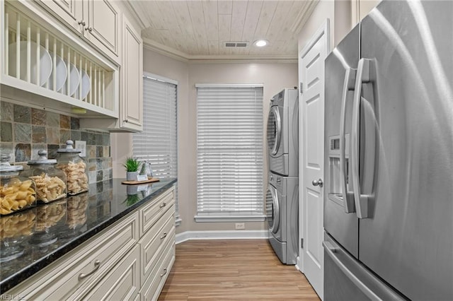 kitchen with stainless steel fridge, stacked washer / drying machine, crown molding, baseboards, and decorative backsplash