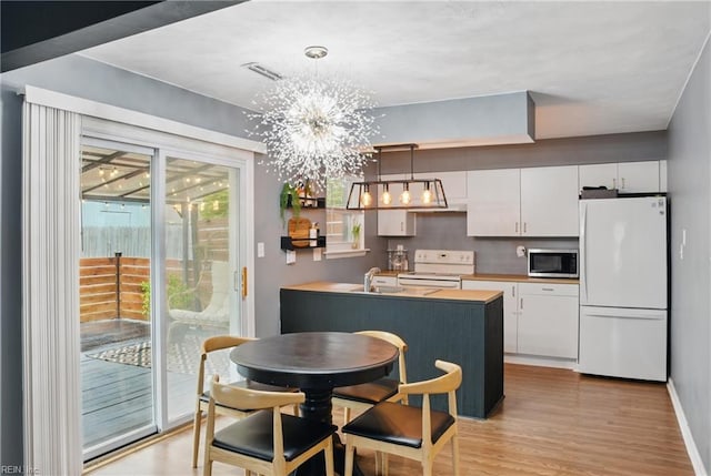 dining room featuring light wood-style floors, a chandelier, and baseboards