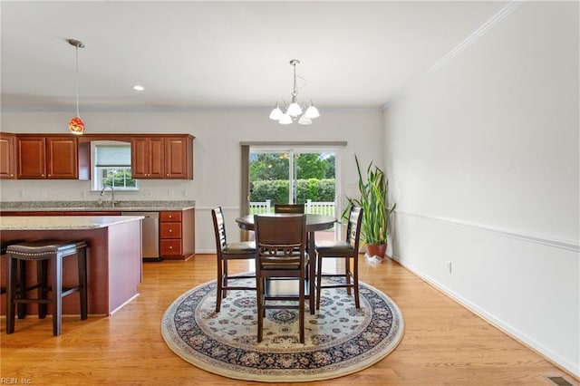 dining room with a chandelier, plenty of natural light, light wood finished floors, ornamental molding, and baseboards