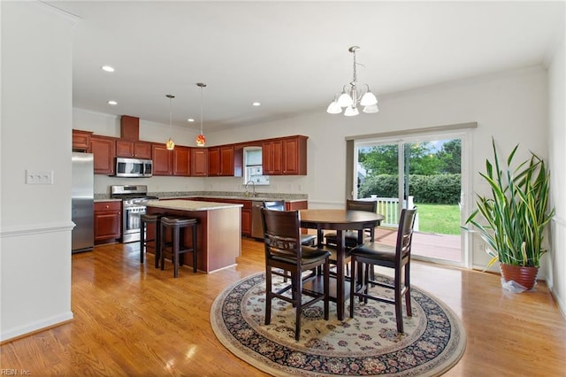 dining space with healthy amount of natural light, light wood finished floors, a chandelier, recessed lighting, and crown molding