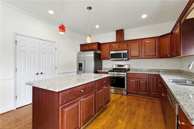 kitchen featuring appliances with stainless steel finishes, a sink, crown molding, dark wood finished floors, and light stone countertops