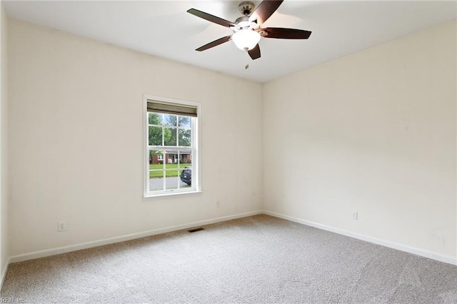 carpeted spare room featuring a ceiling fan and baseboards