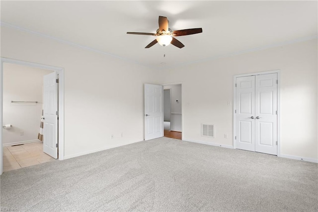 unfurnished bedroom featuring crown molding, light carpet, baseboards, a closet, and a ceiling fan