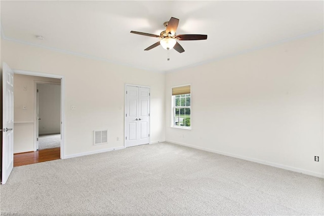 unfurnished bedroom with carpet flooring, baseboards, ornamental molding, a closet, and ceiling fan