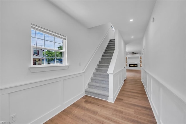 20 Kimberly Ave, Hampton, VA 23663 - stairway with a decorative wall, a lit fireplace, wood finished floors, recessed lighting, and wainscoting