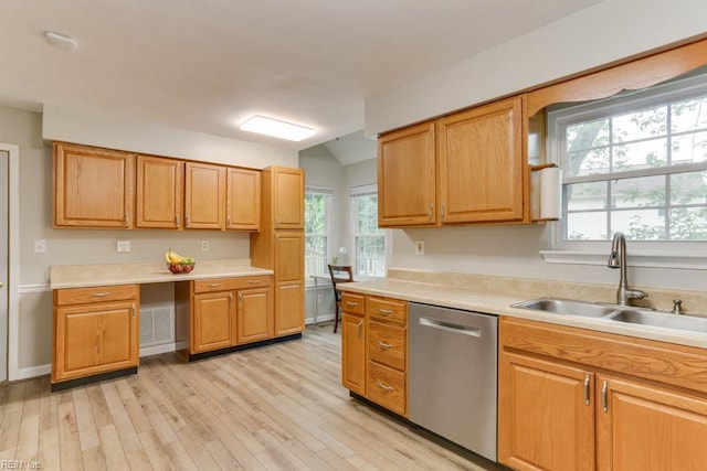 kitchen with stainless steel dishwasher, a sink, light wood-style flooring, and light countertops