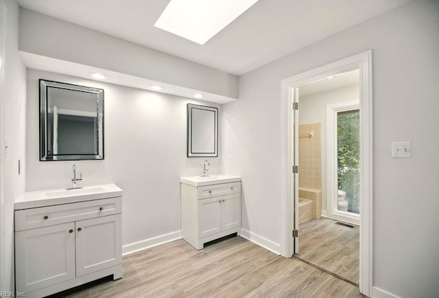 38 Yeardleys Grant, Williamsburg, VA 23185 - bathroom with wood finished floors, two vanities, a skylight, baseboards, and recessed lighting