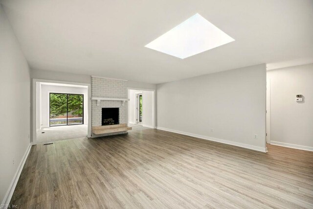 38 Yeardleys Grant, Williamsburg, VA 23185 - unfurnished living room featuring wood finished floors, baseboards, a brick fireplace, and a skylight