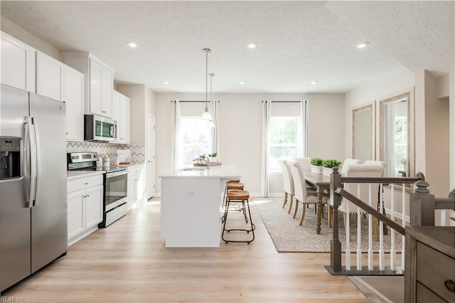 268 Tern Ave, Portsmouth, VA 23701 - kitchen featuring appliances with stainless steel finishes, a kitchen island, decorative backsplash, white cabinets, and a breakfast bar