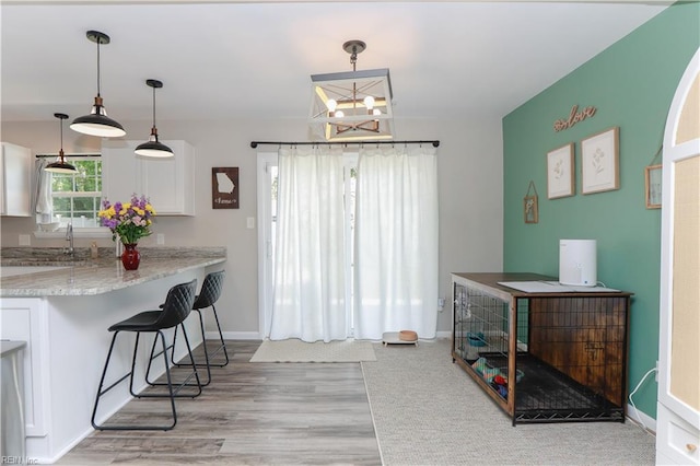 823 Jessie Cir, Newport News, VA 23608 - kitchen featuring light wood finished floors, a chandelier, baseboards, white cabinetry, and a breakfast bar area