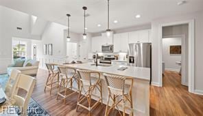 3509 Elaina Way, Chesapeake, VA 23321 - kitchen featuring stainless steel appliances, white cabinets, wood finished floors, a kitchen bar, and recessed lighting