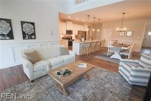 3509 Elaina Way, Chesapeake, VA 23321 - living area featuring wood finished floors, a chandelier, a wainscoted wall, and a decorative wall