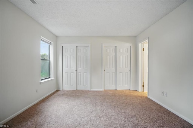 8530 Tidewater Dr Unit 111, Norfolk, VA 23503 - unfurnished bedroom featuring two closets, carpet flooring, a textured ceiling, and baseboards