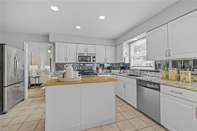 kitchen with appliances with stainless steel finishes, a sink, light tile patterned flooring, white cabinets, and recessed lighting