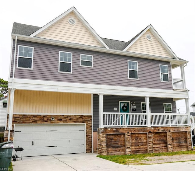view of front of home with covered porch, stone siding, roof with shingles, and an attached garage