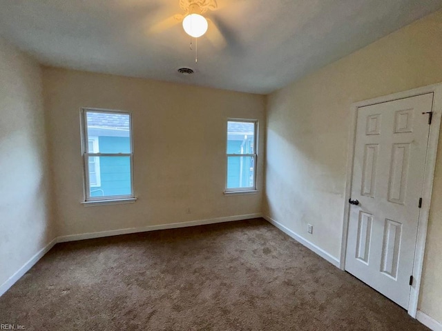 carpeted empty room featuring baseboards and a ceiling fan