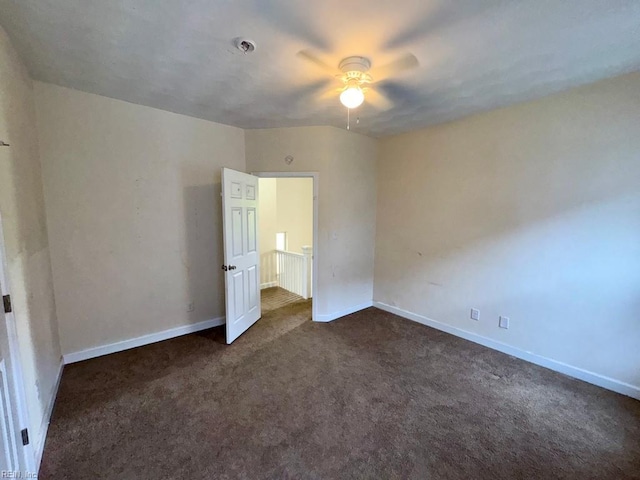 unfurnished bedroom with dark colored carpet, baseboards, and ceiling fan