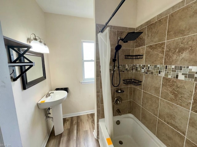 full bath featuring wood finished floors, shower / bath combination with curtain, baseboards, and a sink