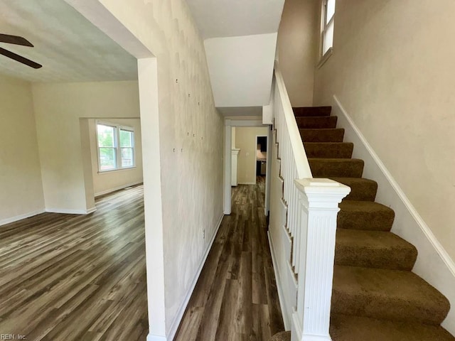 stairway with ceiling fan, wood finished floors, and baseboards